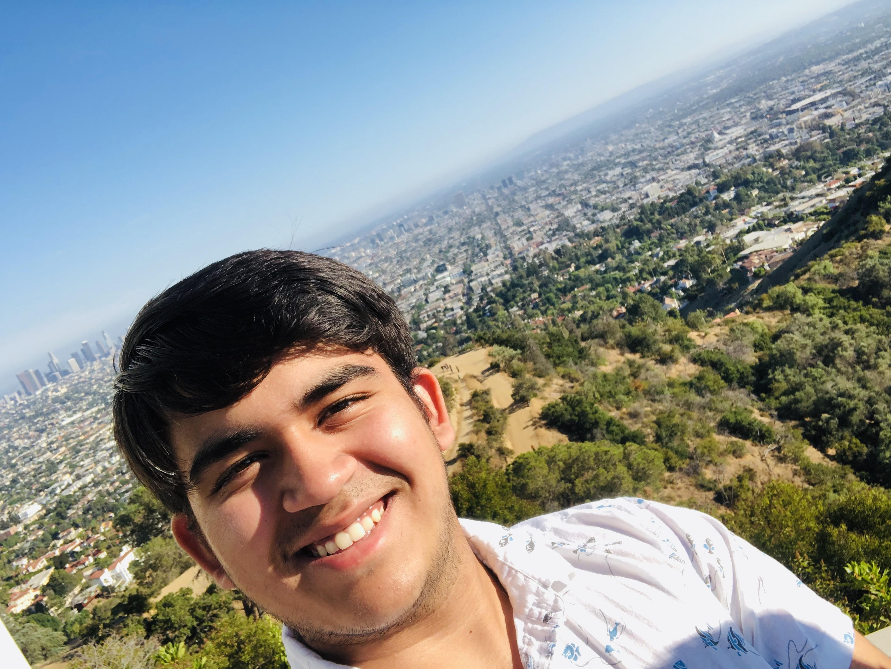 Portrait of Uzair Gheewala smiling in front of a neutral background.